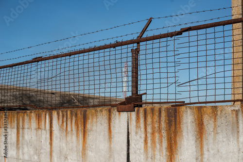 Fence with barbed wire on a background of blue clear sky.