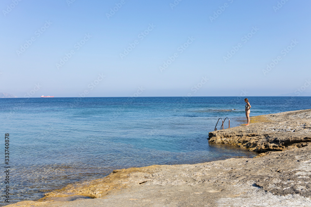 Woman looking the sea in a rocky coast