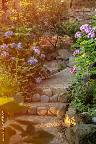 Land improvement: path in the garden with steps decorated with natural sea stones at sunset