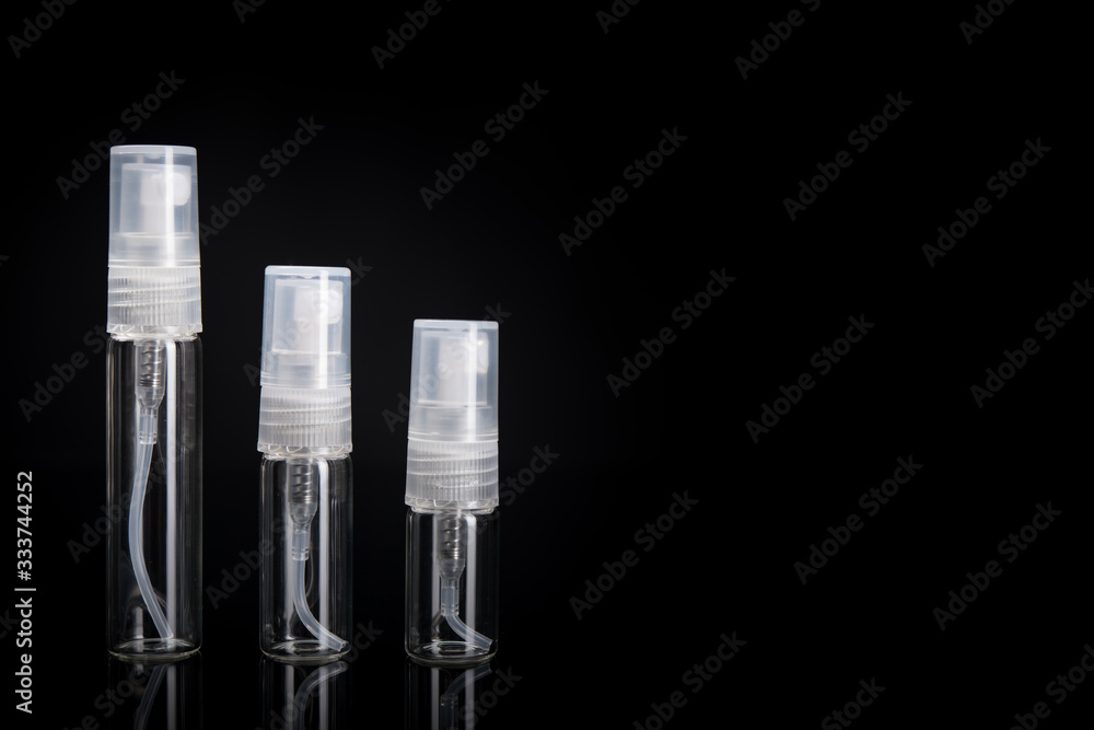 Glass bottle with spray atomizer. Bottles good for perfume samples or other liquids. Travel size 5ml, 3ml, 2ml. On black background with copy space. Glass bottle with spray atomizer. Bottles good for perfume samples or other liquids. Travel size 5ml, 3ml, 2ml. On black background with copy space.