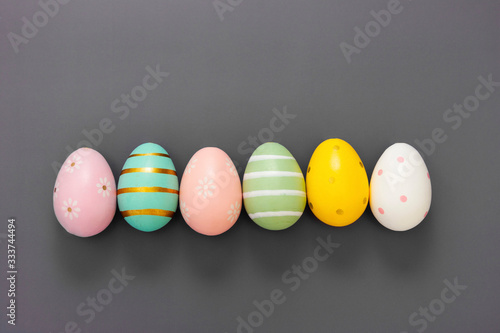 Easter eggs in row, decorative abstract colorful eggs. Over grey background, top view.