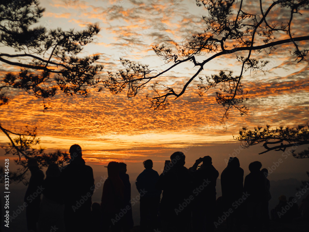 Silhouette of tourist group Stand and watch the sun by the cliff