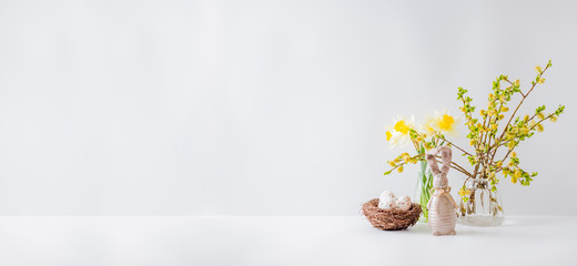 Home interior with easter decor. Willow branches in a glass vase, easter eggs on a light background