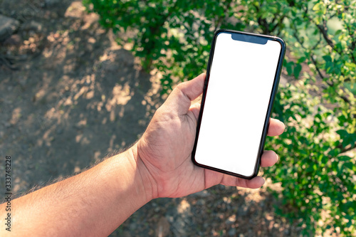 Asian man holding phone mock up right frame at park outdoor have nature plant green background isolated display for insert screen