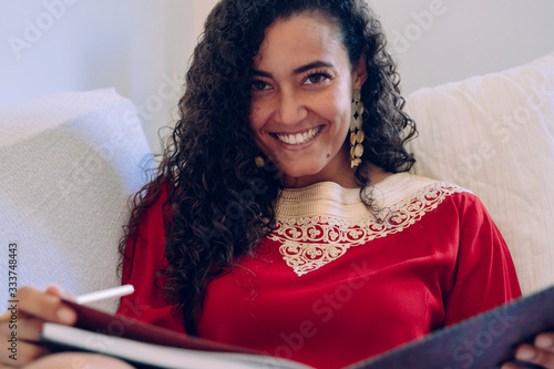Obraz na plátně Beautiful ethnic woman writing on a notebook at home