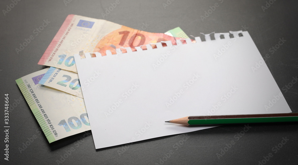 Blank note paper, euro banknotes and pencil on blackboard, chalkboard black Blank note paper, euro banknotes and pencil on blackboard, chalkboard black