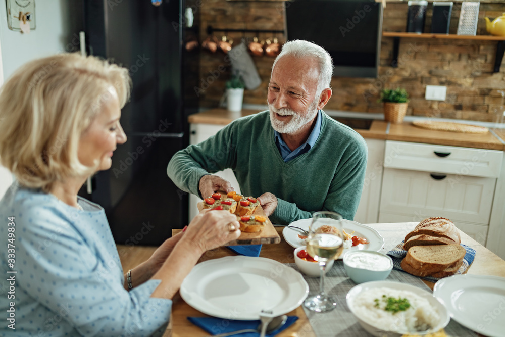 Happy mature couple having lunch together in dining room. Happy mature couple having lunch together in dining room.