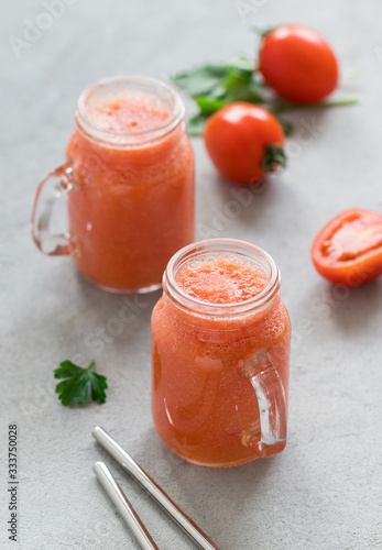 Tomato smoothie with parsley in a jar on a light background