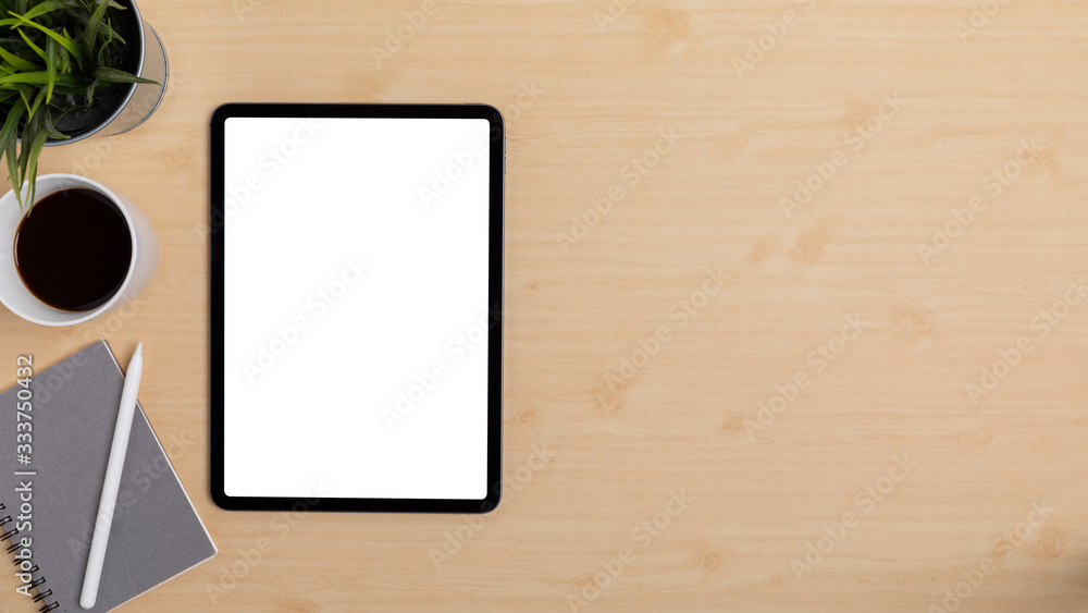 Wooden Table Office desk top view design workspace layout left have plant, coffee cup, pen on top notebook, show mock up tablet isolated and empty right area for insert text or other Wooden Table Office desk top view design workspace layout left have plant, coffee cup, pen on top notebook, show mock up tablet isolated and empty right area for insert text or other