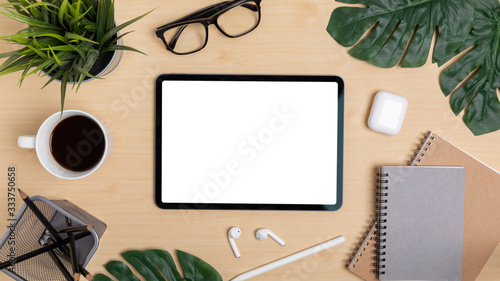 Wooden Table Office desk top view design workspace layout center show mock up tablet isolated for insert on screen around space have leaf, notebook, pen, earphones, coffee cup, plant, glasses photo
