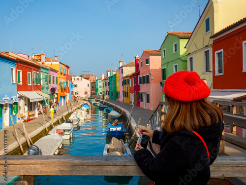 Female tourist taking picture at colourful buildings at Burano, Venice,  Italy 