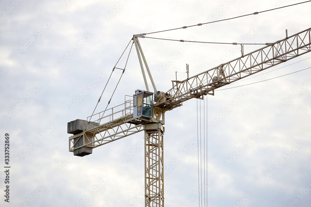 Tower cranes work during the construction of a multi-story building. New apartments for residents and premises for offices. Risky work at height. Lifting heavy building materials. City development