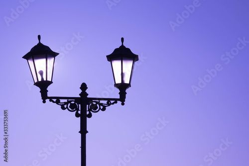 Urban landscape. Street lamp with a lamp in a classic style against a purple sky. Beautiful postcard.