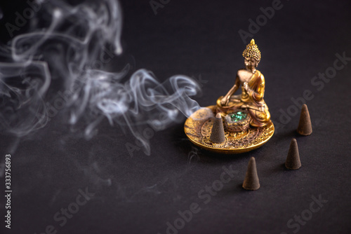 Aromatic cone on beautiful buddha holder burning and creating smoke.