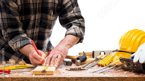 Close-up. Carpenter with pencil and the meter marks the measurement on a wooden board. Construction industry. Isolated on a white background.