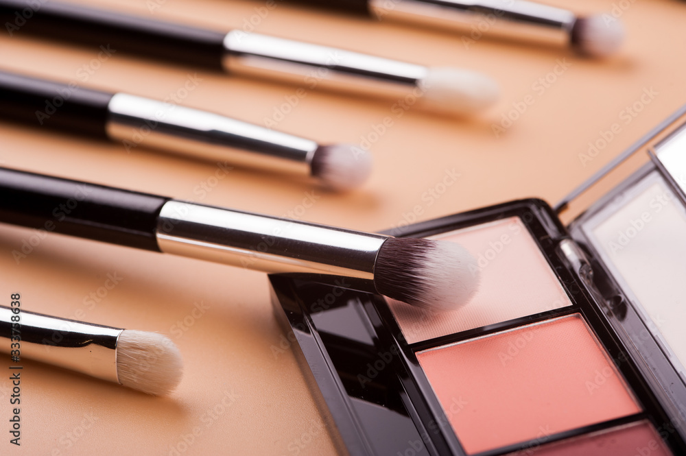 Cosmetic palette with brushes lies on a beige background Cosmetic palette with brushes lies on a beige background