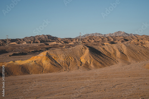 High voltage power lines of Aqaba in the sunset light on the sandstone supply electricity to the city.