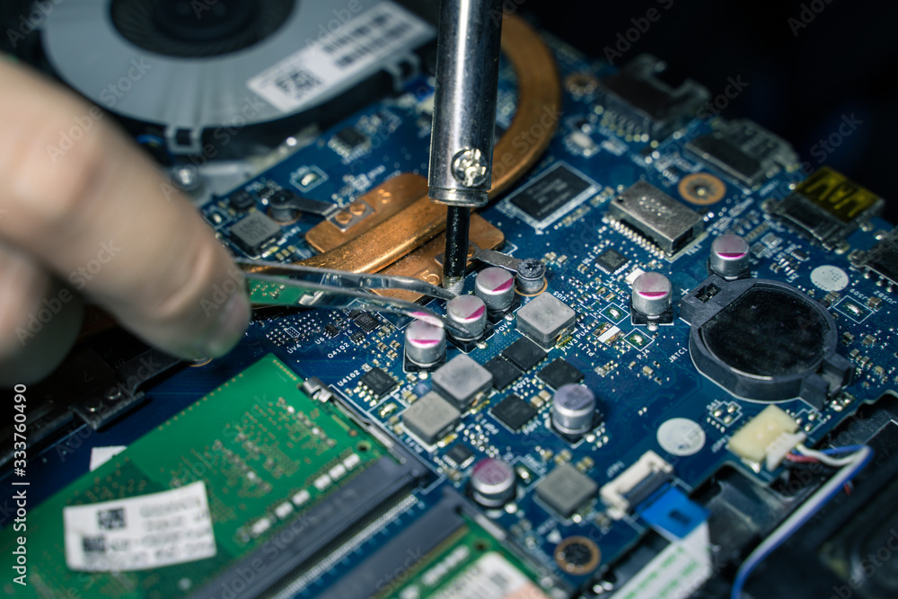 A close-up of an electrician repairing a computer circuit board,close up electrician hands are working with soldering iron A close-up of an electrician repairing a computer circuit board,close up electrician hands are working with soldering iron