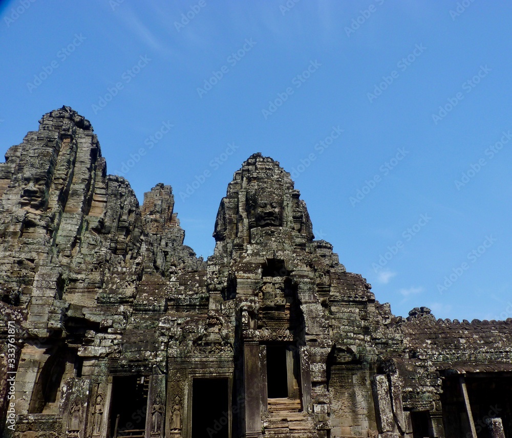 Ruins of Angkor, face tower of Bayon temple against blue sky, Angkor Wat, Cambodia