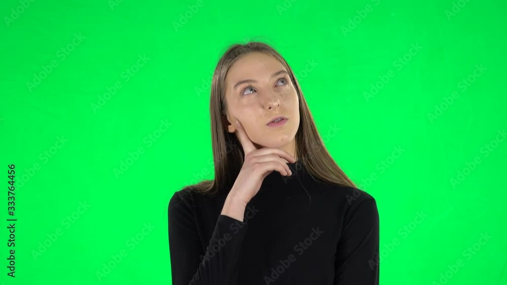 Portrait of awkward teenage girl is wearing braces is daydreaming and smiling looking up on a green screen Portrait of awkward teenage girl is wearing braces is daydreaming and smiling looking up on a green screen