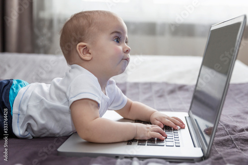 The baby looks with interest at the laptop screen. New generation. © Анна Демидова