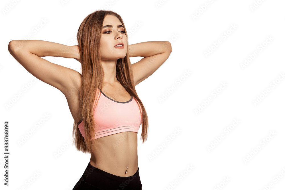 Beautiful young woman in sportswear standing on a white isolated background. Keep your hands in the castle behind your head. Warm up, stretching. Tightened body. Fitness model. Pose. Copy space. Beautiful young woman in sportswear standing on a white isolated background. Keep your hands in the castle behind your head. Warm up, stretching. Tightened body. Fitness model. Pose. Copy space.