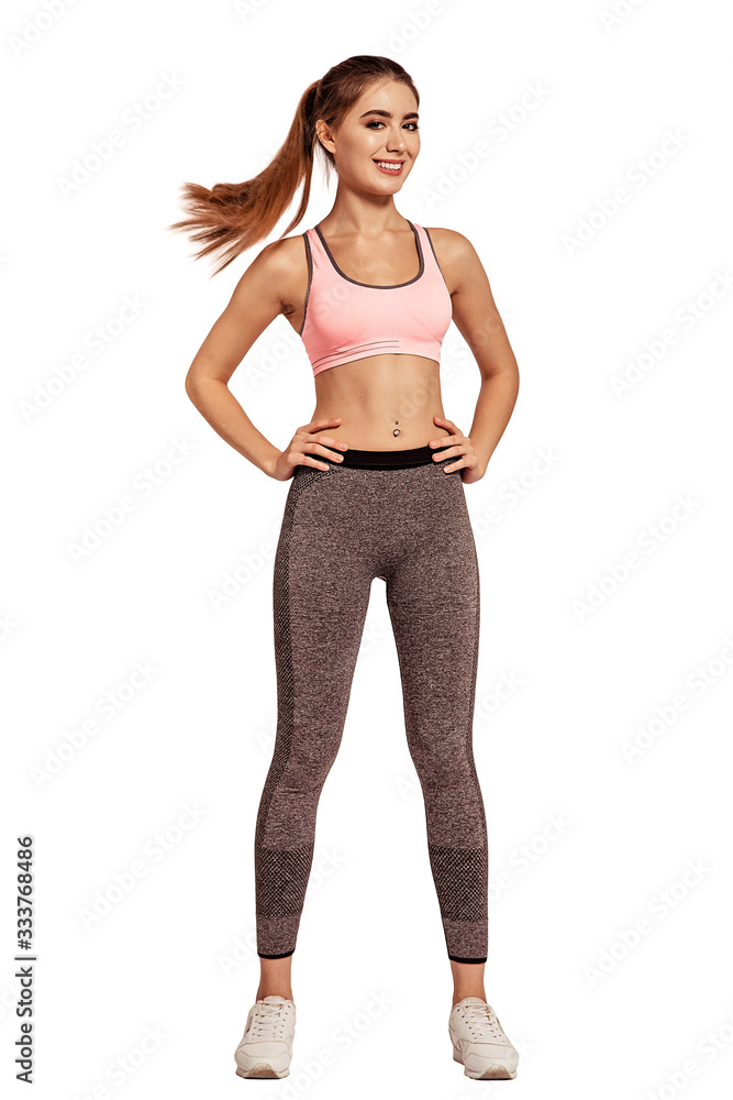 Beautiful, young woman standing in a sportswear, top and leggings. Tight, athletic body, thin, flat stomach. Caucasian appearance. Drying. Pose. Do fitness. Cheerful smile. White background, isolated. Beautiful, young woman standing in a sportswear, top and leggings. Tight, athletic body, thin, flat stomach. Caucasian appearance. Drying. Pose. Do fitness. Cheerful smile. White background, isolated.