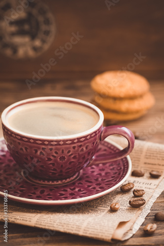 Cup of coffee with beans on newspaper background, business breakfast concept, selective focus, toned vintage