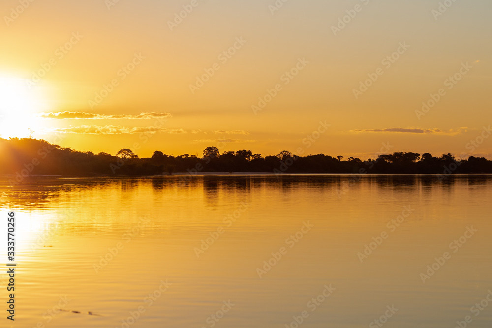 The lush sunset of autumn afternoons in the Brazilian savannah at Praia do Sol, on the banks of the Rio do Coco, a tributary of the Araguaia River.
