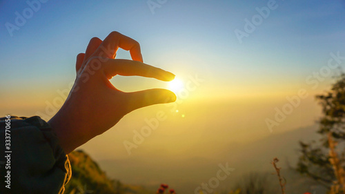 silhouette of hands with beautiful evening sunrise light in hand and blue skyline