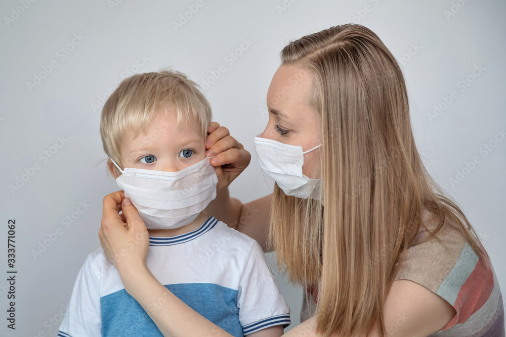 Woman with a medical mask puts it on a child