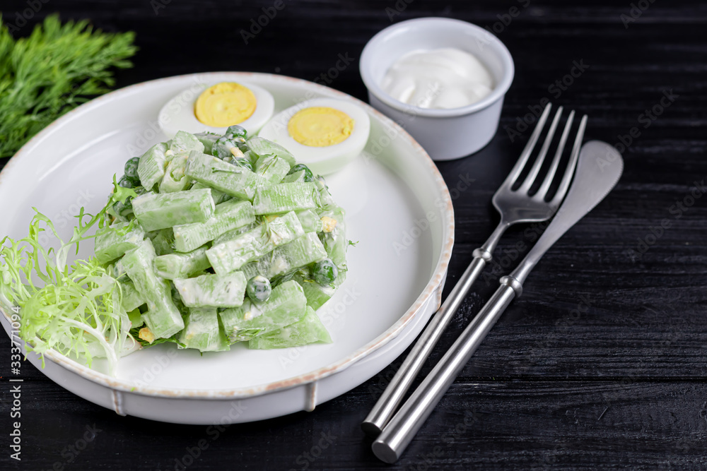 Salad of fresh cucumbers, spinach leaves, arugula, avocado. Served with slices of eggs and red pepper. Dietary nutrition. Breakfast for the whole family. Vitamin plate. On a dark wooden background. Salad of fresh cucumbers, spinach leaves, arugula, avocado. Served with slices of eggs and red pepper. Dietary nutrition. Breakfast for the whole family. Vitamin plate. On a dark wooden background.