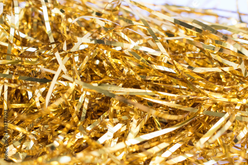 Surface covered with the golden tinsel garland as an abstract background texture. Bokeh effect.
