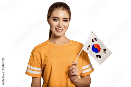 A beautiful young woman holds in her hands the flag of Korea. Exchange student, learn language. Tourist traveling. White background. Isolate. Football fan. photo