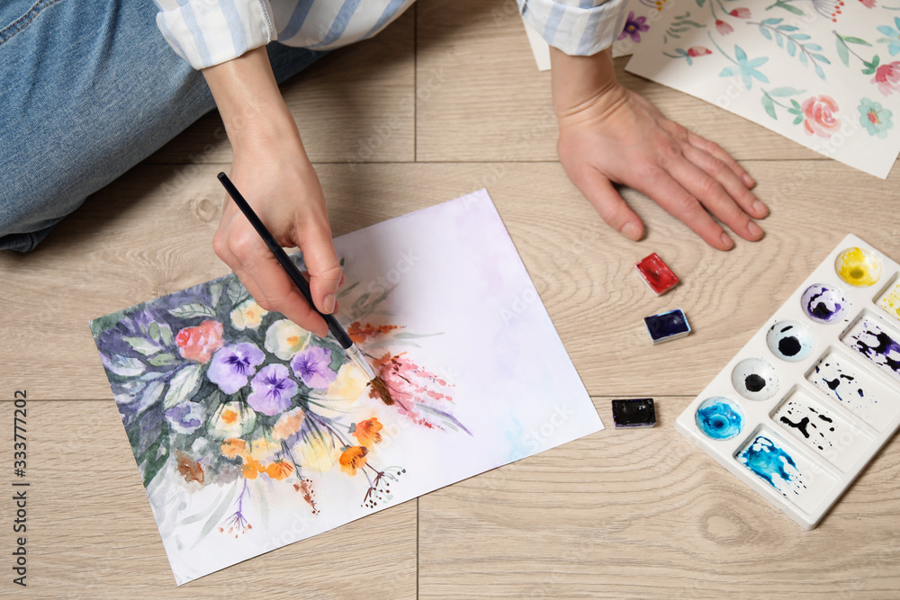 Obraz premium Woman painting flowers with watercolor on floor, closeup