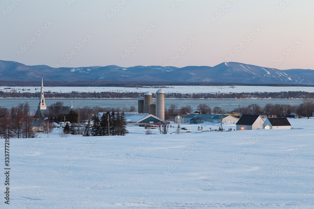 Picturesque village with the St. Lawrence River and the Laurentian mountains in the background seen during a blue hour morning, St. Michel-de-Bellechasse, Quebec, Canada