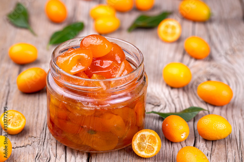 Homemade kumquat jam in plate and fresh kumquats, top view