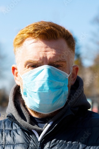 A man in a surgical mask standing outdoor. Coronavirus infection protection kit. Rapidly spreading corona pandemic.
