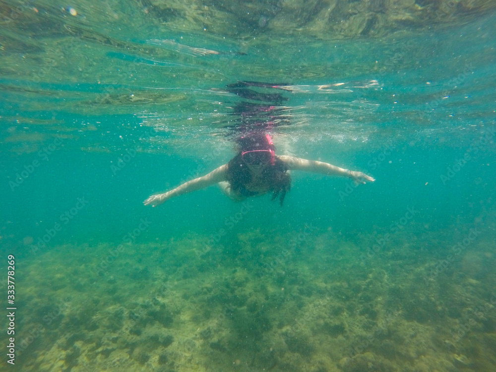 menina em mergulho no mar com recife de corais