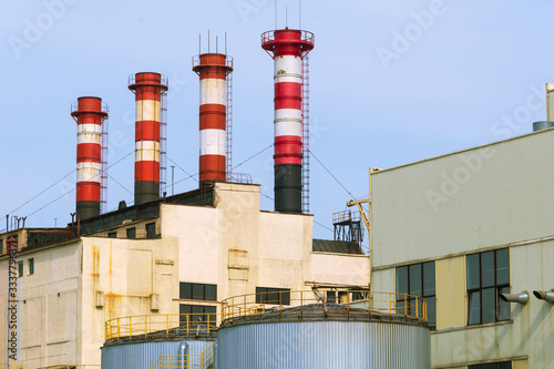 high factory exhaust pipes against a blue sky, urban air pollution