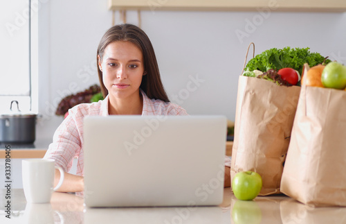 Smiling woman online shopping using tablet and credit card in kitchen . Smiling woman