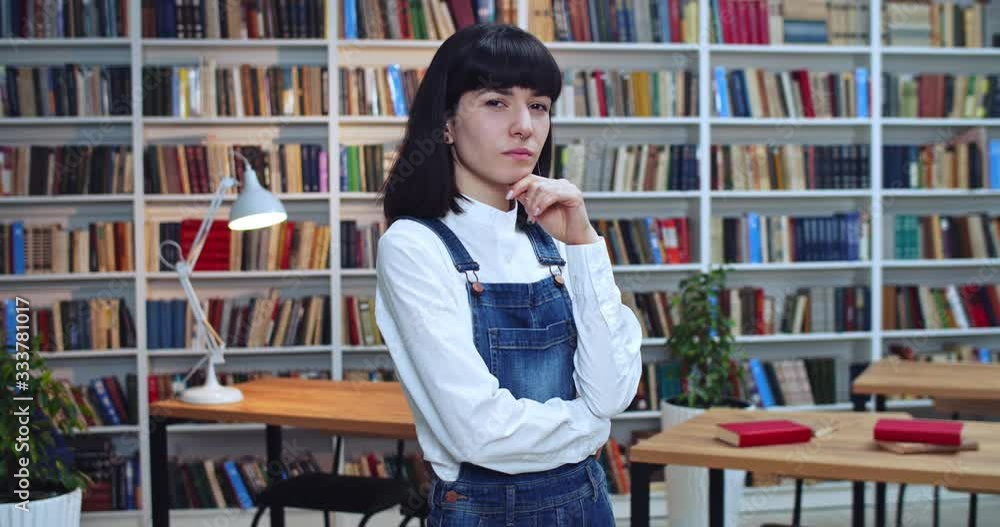 Close-up portrait of posh confident girl getting some ideas in the library. Bookcase in background. Close-up portrait of posh confident girl getting some ideas in the library. Bookcase in background.
