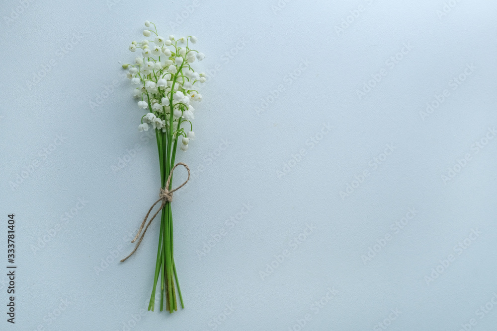 Small bouquet of lilies of the valley with craft rope on white background, top view