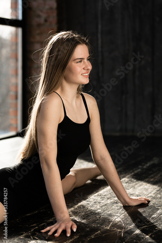 Close-up Athletic girl in sports wear sits on a split. Gymnast does stretching before exercise at the morning