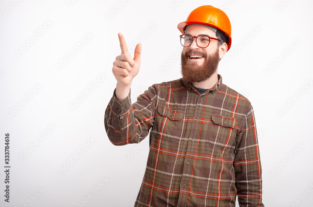 Young bearded builder engineer or architect is pointing forward on white background. Young bearded builder engineer or architect is pointing forward on white background.