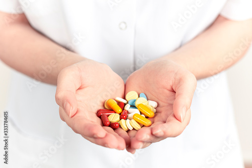 In the doctor's hand, A handful of various colored pills and vitamin pills.