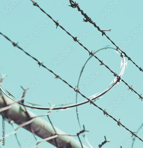 Barbed wire and razor wire on chain link fence. Security, prison, obstacle, difficulty concepts.