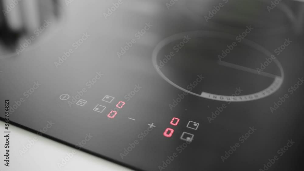 Woman hand starts the induction cooker Woman hand starts the induction cooker
