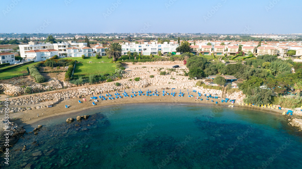 Aerial bird's eye view of Sirena beach in Protaras, Paralimni, Famagusta, Cyprus. The famous Sirina bay tourist attraction with sunbeds, golden sand, restaurant, people swimming in the sea from above.
