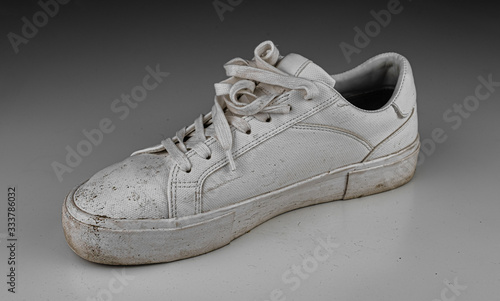 Dirty, used, muddy white right shoes on white dirty floor